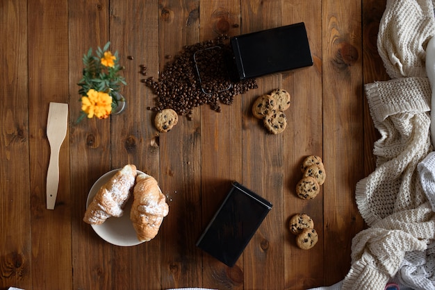 Coffee grain sprinkled on a wooden table with croissants