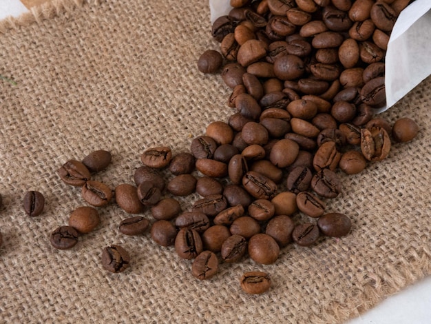 Coffee grains are poured from a cup to a canvas napkin