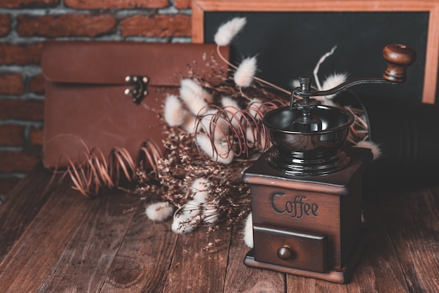 Foto macinacaffè e beens del caffè nella decorazione della tela da imballaggio con il fiore e la lavagna secchi