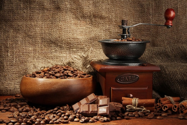 Coffee grinder and cup of coffee on burlap background