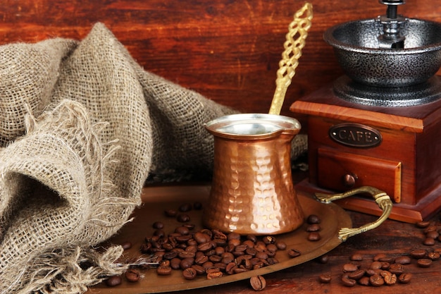 Coffee grinder turk and coffee beans on golden tray on wooden background