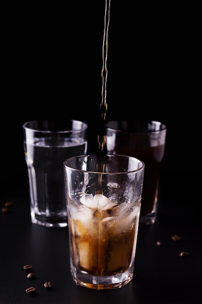 Coffee is poured into a glass with ice