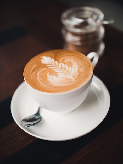 Coffee latte art in cafe with woman hand