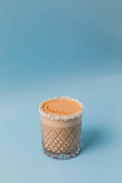 Кофе лате капучино какао в стакане с кокосовым краем на синем фоне молочная пена с лате арт копировать пространство