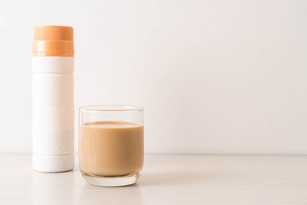 Foto bicchiere di caffè latte con bottiglie di caffè pronte da bere sul tavolo