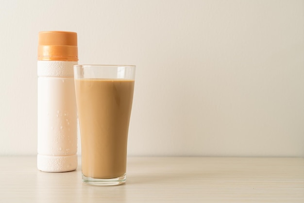 Foto bicchiere di caffè latte con bottiglie di caffè pronte da bere sul tavolo