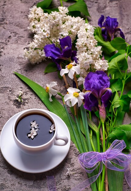 Coffee and lilac flowers on grey concrete background