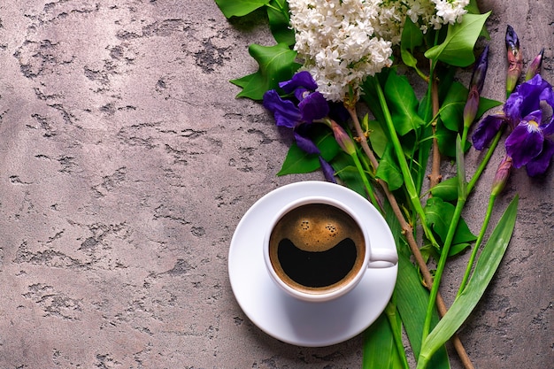 Coffee and lilac flowers on grey concrete surface