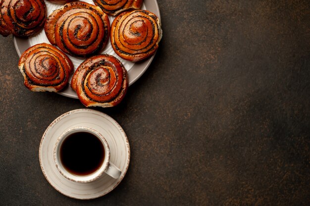 Photo coffee and a lot of buns with poppy seeds on a stone background