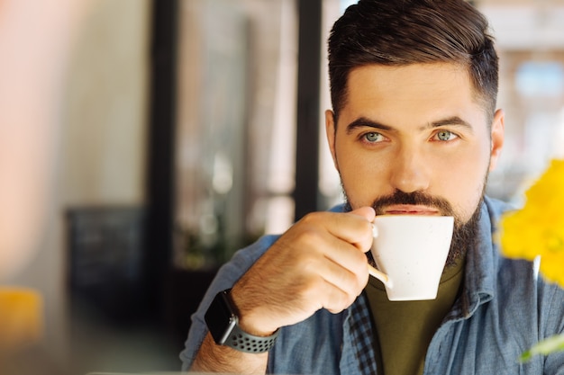 コーヒー愛好家。おいしいコーヒーを飲みながらハンサムなブルネットの男の肖像画
