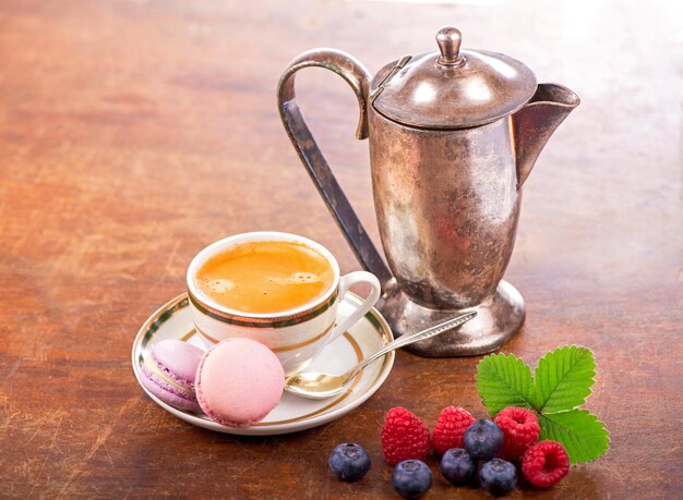 Coffee and macarons with berries on a wooden table on a wooden background