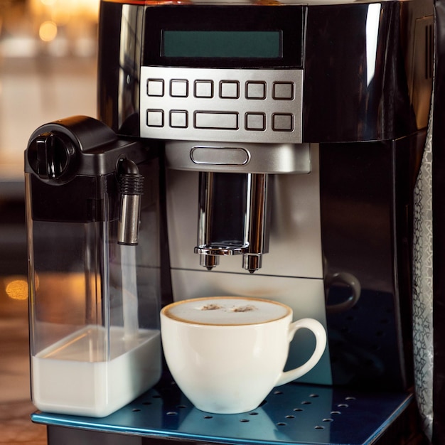 흰색 컵이 있는 커피 머신을 닫습니다.