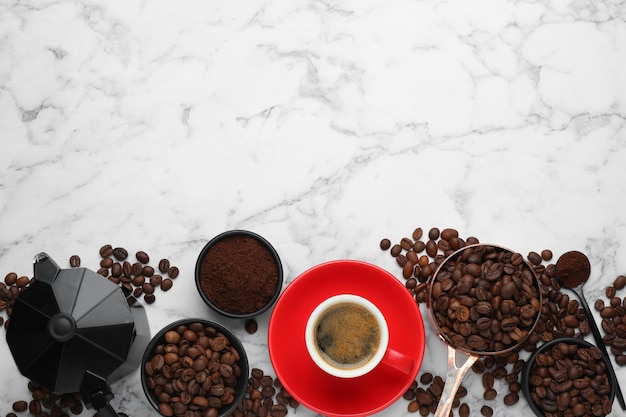 Coffee maker beans powder and cup of drink on white marble table flat lay Space for text