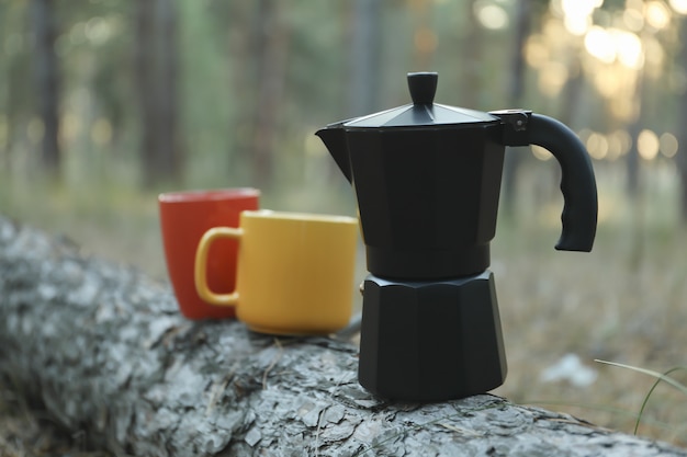 소나무 줄기에 커피 메이커와 컵입니다. 아름다운 숲, 텍스트를위한 공간