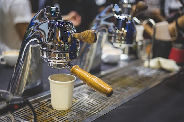 カフェで使い捨てカップを満たすコーヒーメーカー