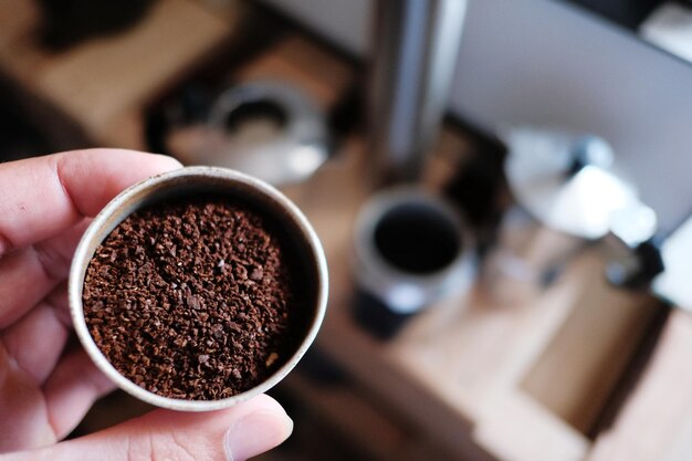 コーヒーメーカーがコーヒー豆を混ぜてコーヒー粉をモカポットに入れる準備をしています