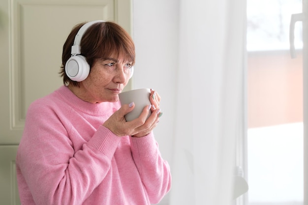 Coffee and melodies cheerful senior lady by the window lifes simple pleasures