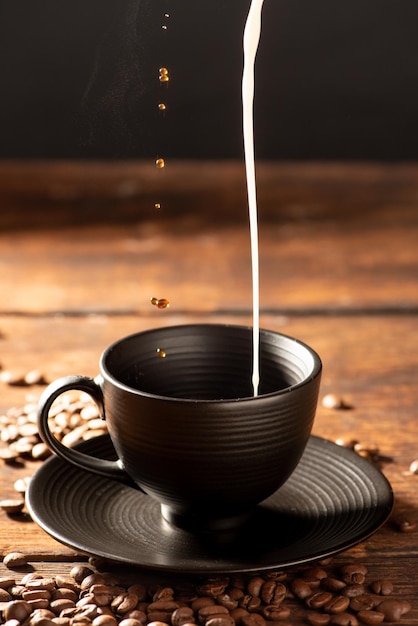 Coffee and milk pouring latte into a black cup dark food style photo selective focus