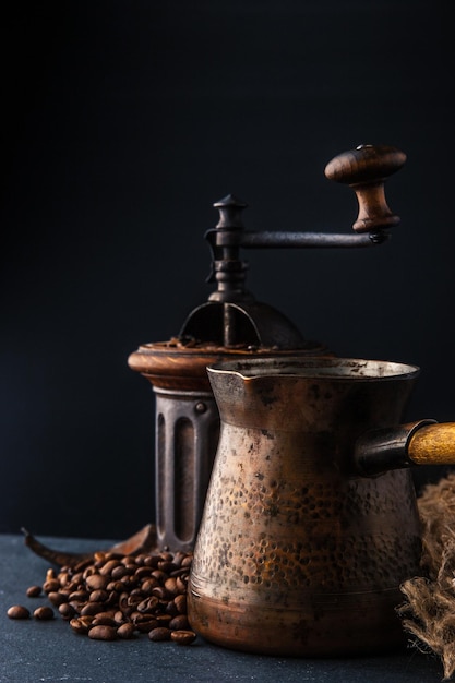 Photo coffee mill and cezve on the dark table vertical