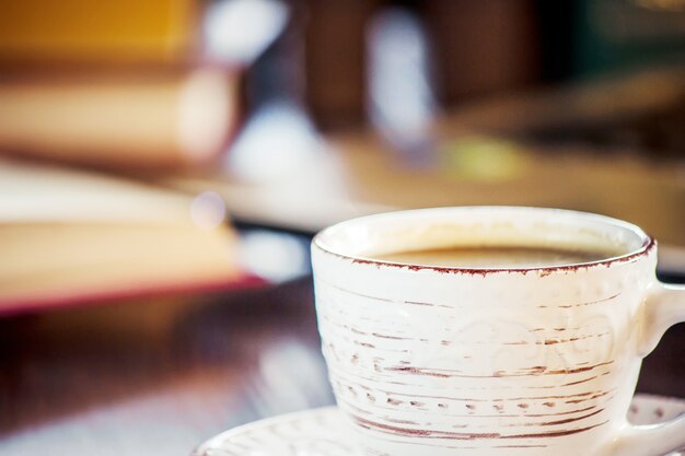 Foto caffè mattutino sul posto di lavoro. con un libro o un laptop. messa a fuoco selettiva.