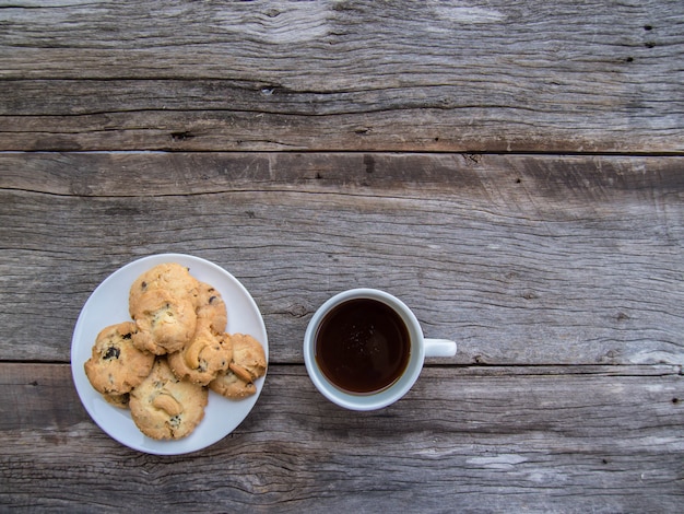 写真 コーヒーマグと白いプレートは古い木製の床にクッキーを置く