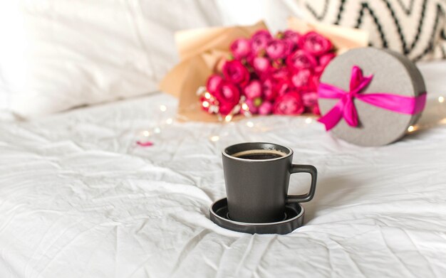 Coffee mug in bed on the background of a bouquet of flowers a gift concept of valentines day march  ...