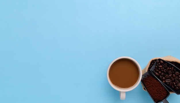 Coffee mug, coffee beans, ground coffee on a blue background