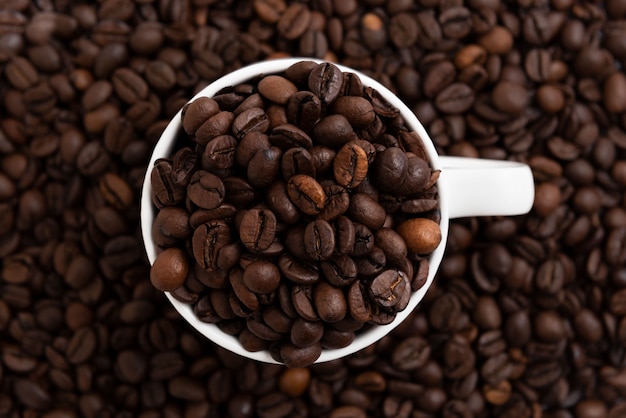 Photo coffee mug fulled of coffee beans top view