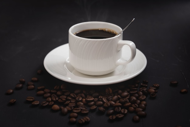 Foto tazza da caffè isolata con alcuni fagioli su sfondo nero