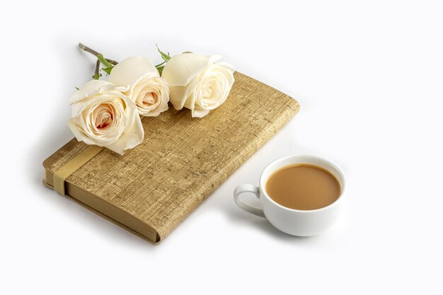 coffee mug, notebook (notepad) and white roses. Female workplace
