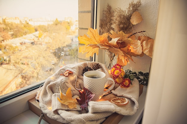 Coffee mug surrounded by sweaters and autumn decor