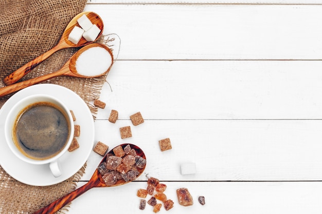 Coffee mug with slices of sugar on wooden table background