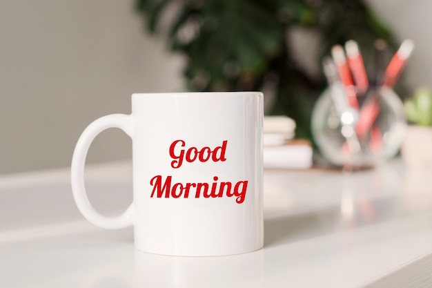 Coffee mug with text GOOD MORNING in workplace background