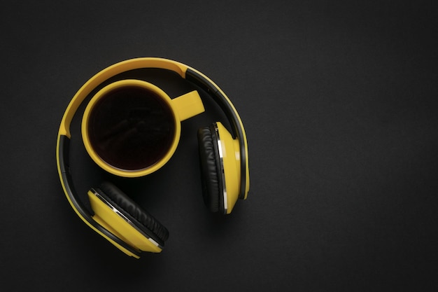 검은색 바탕에 커피 컵과 노란색 헤드폰 텍스트를 위한 공간 스타일리시한 작업장의 개념