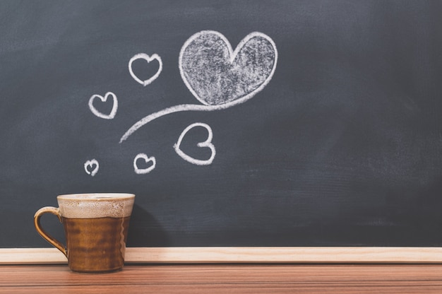 Coffee mugs and heart shapes on the blackboard