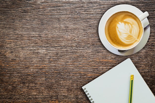 above coffee and notebook with pencil on wood texture 