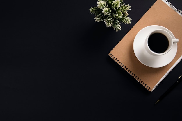 Coffee on notepad with flower on black table