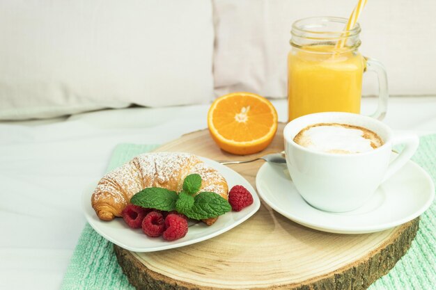 Foto succo d'arancia al caffè e un croissant su un gambo di legno