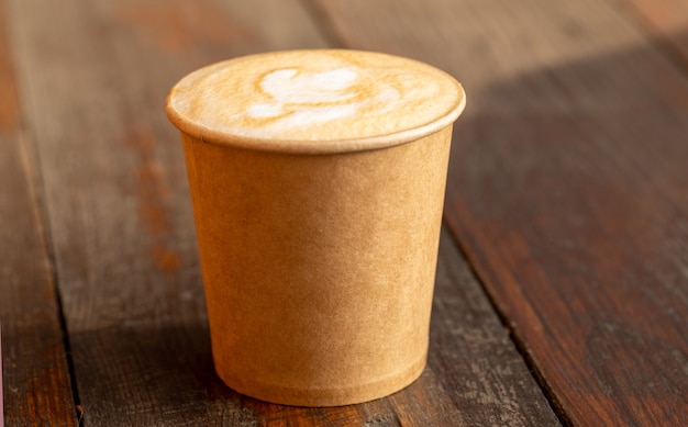 Coffee in a paper cup on a wooden table