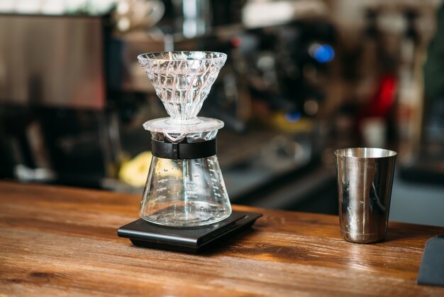 Coffee pot and metal glass on a bar counter.