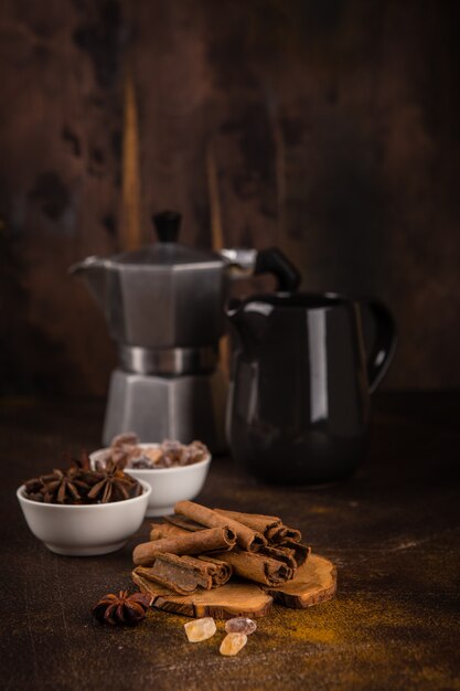 Coffee pot with spices on brown background.