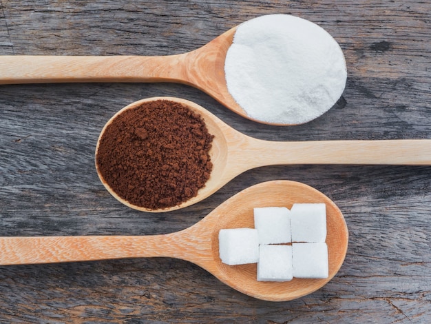 Coffee and powdered milk with sugar cubes on wooden spoon