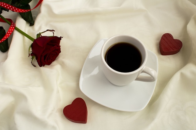 Coffee, red hearts and rose in the white bed