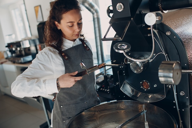 Coffee roaster machine and barista with tryer at coffee roasting process.