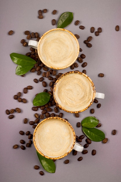 Coffee in rustic cups among grains and green coffee leaves.