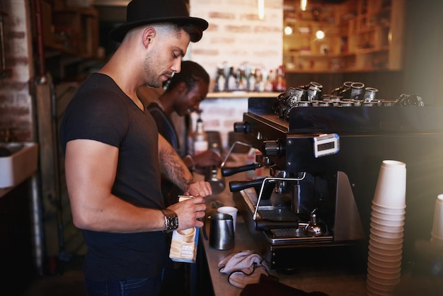 コーヒーに精通しているカフェでコーヒーマシンを操作している若い男のショット