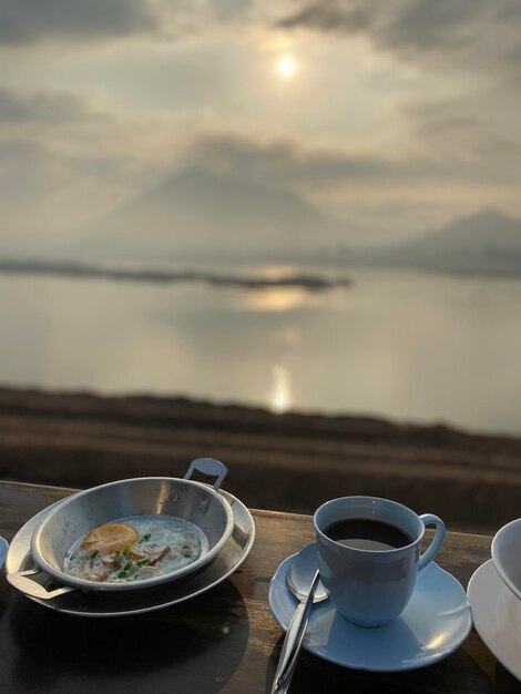 Foto caffè servito sulla tavola dal mare contro il cielo