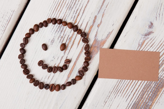 Coffee smiley face and blank paper for your text. White wooden planks on surface.