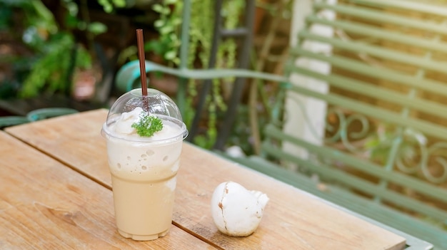 Coffee smoothie on a wooden table and plant background.