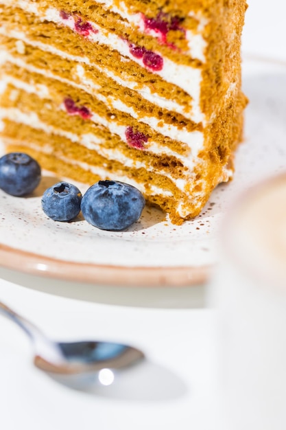 Coffee, spoon, blueberry, a slice of cake on the plate on the white background.